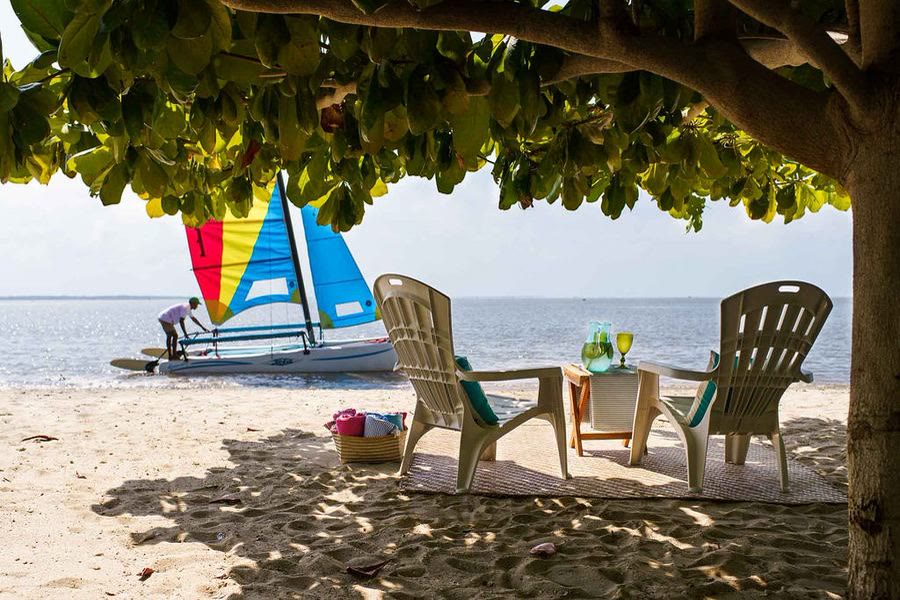 Chaises sur une plage de sable avec un voilier sur l'eau