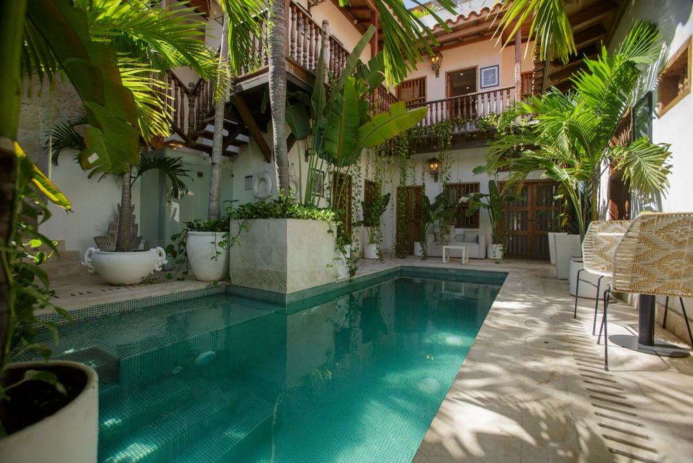 Piscine d'un patio entourée de plantes en pot et de dalles de pierre